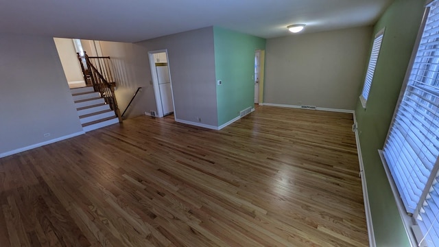 spare room with wood finished floors, visible vents, and baseboards