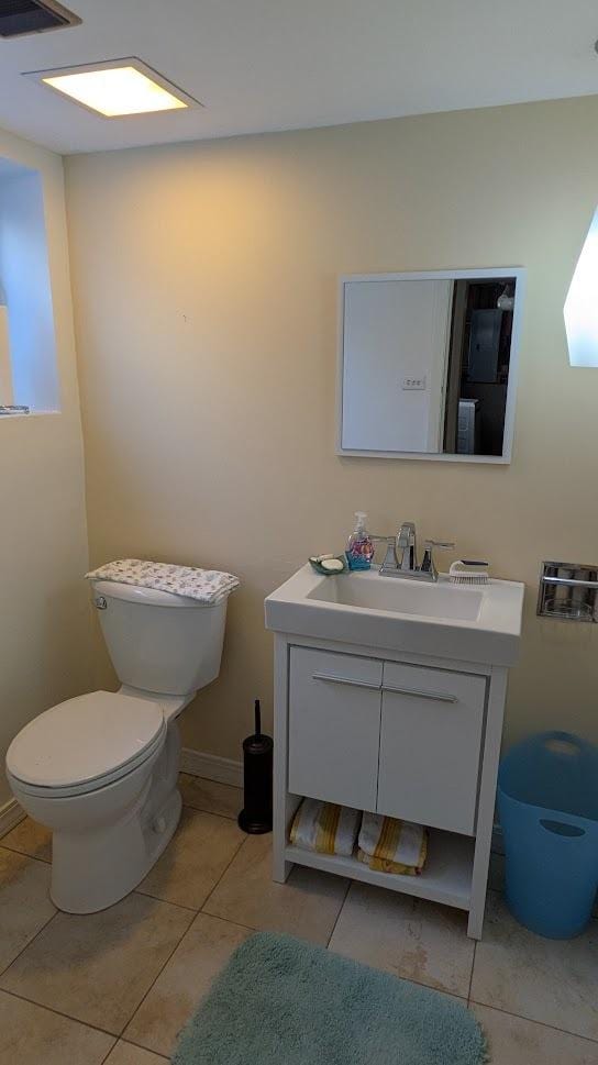 half bathroom featuring toilet, baseboards, vanity, and tile patterned floors