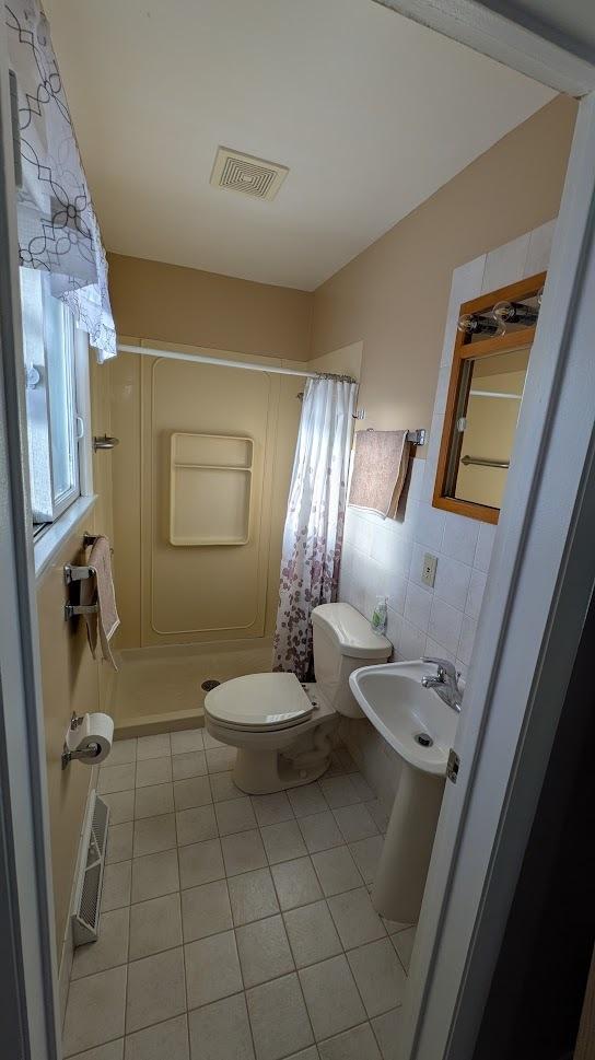 full bath with tile patterned flooring, visible vents, tile walls, and toilet