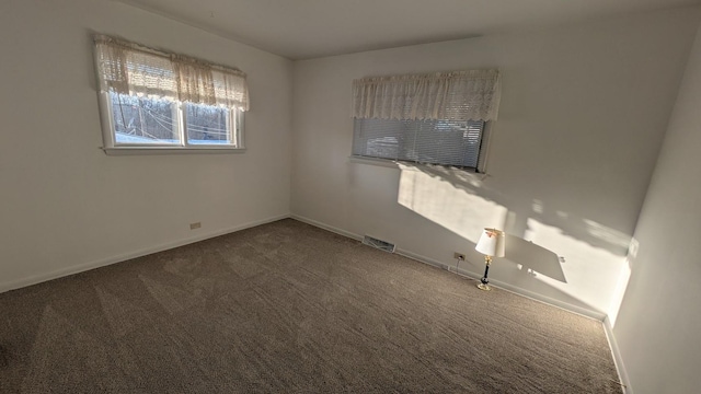 carpeted empty room featuring visible vents and baseboards