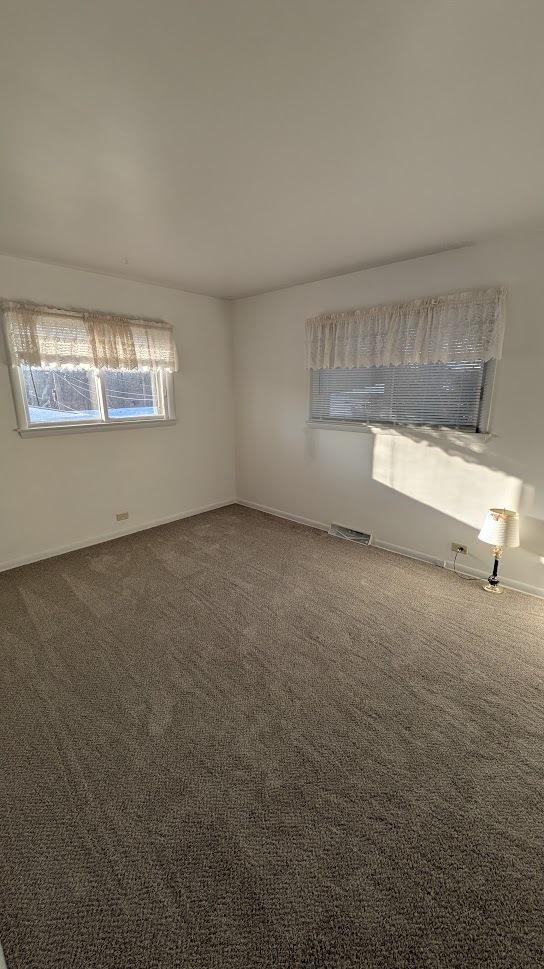 empty room with carpet floors and visible vents