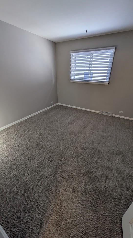 empty room with dark carpet and baseboards