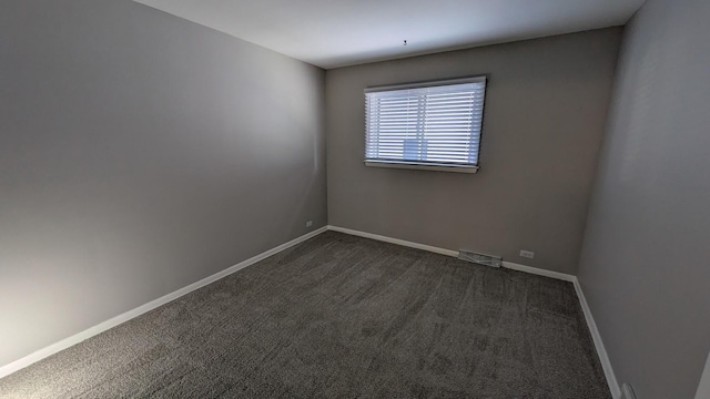 empty room featuring dark colored carpet, visible vents, and baseboards