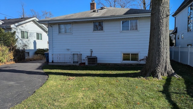 back of property with a lawn, a chimney, and fence