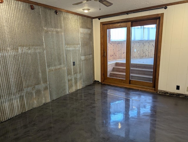 empty room featuring a textured ceiling, finished concrete flooring, ornamental molding, and a ceiling fan