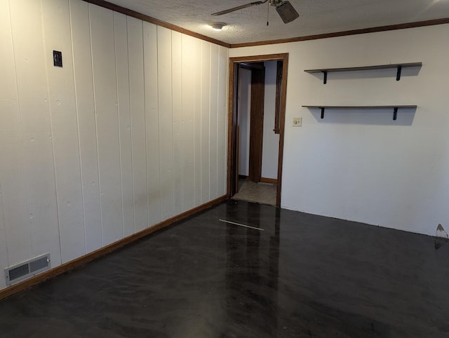 spare room with finished concrete flooring, visible vents, ceiling fan, crown molding, and a textured ceiling