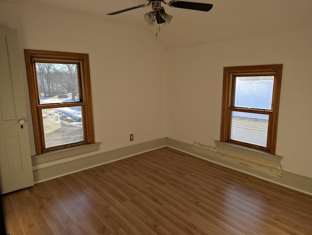 unfurnished room featuring lofted ceiling, plenty of natural light, and wood finished floors