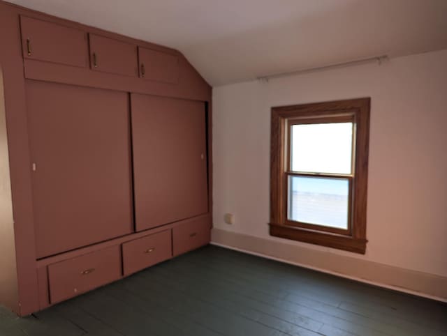 unfurnished bedroom with dark wood-style floors, a closet, and vaulted ceiling