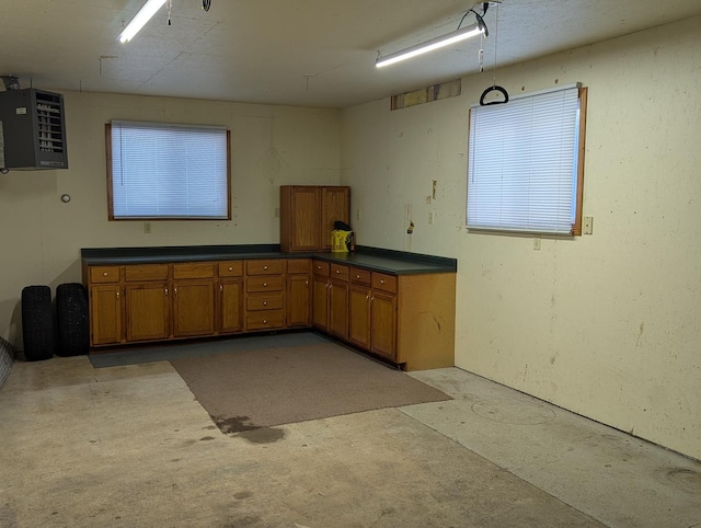 kitchen featuring concrete floors, brown cabinetry, and dark countertops