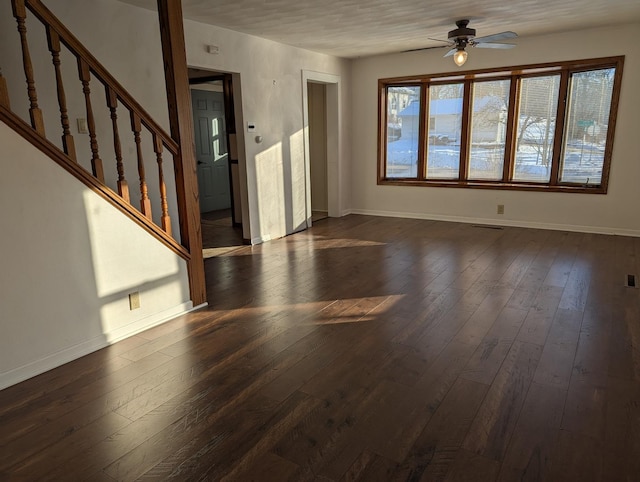 unfurnished living room with dark wood finished floors, a ceiling fan, and baseboards