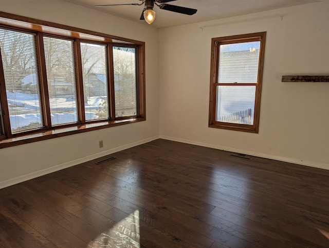 empty room with a ceiling fan, baseboards, visible vents, and dark wood-style flooring