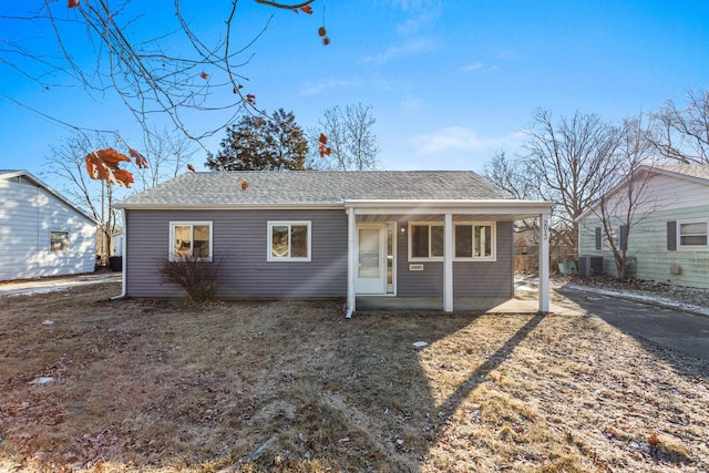 back of property with covered porch and a shingled roof