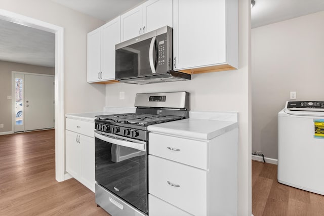 kitchen featuring light wood-style flooring, white cabinetry, light countertops, appliances with stainless steel finishes, and washer / clothes dryer