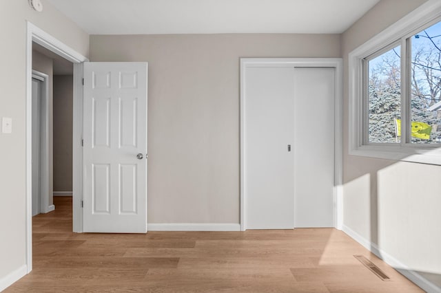 unfurnished bedroom featuring a closet, visible vents, baseboards, and light wood finished floors