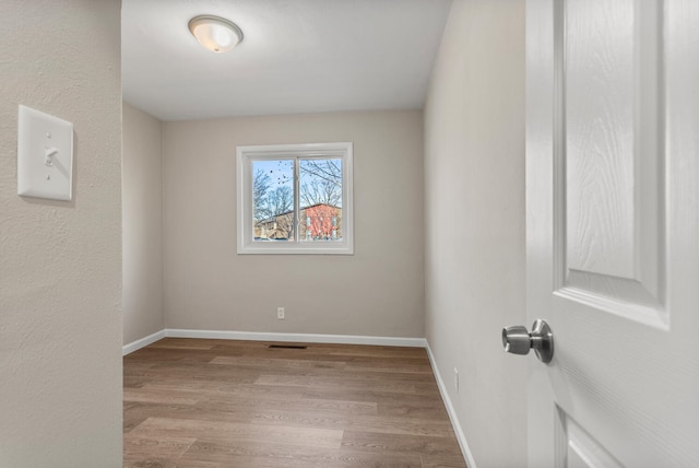 spare room featuring light wood-style floors and baseboards