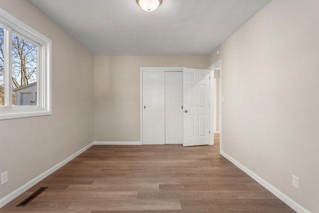 unfurnished bedroom with light wood-type flooring, baseboards, visible vents, and a closet