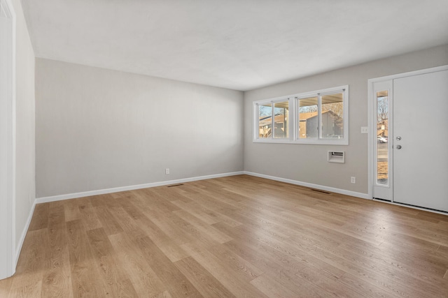 spare room with light wood-style floors, visible vents, and baseboards