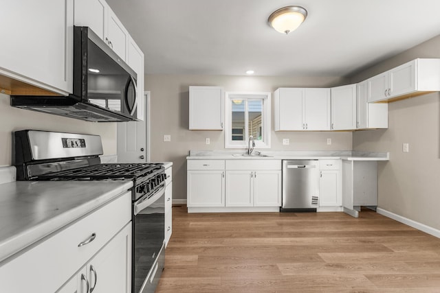 kitchen featuring appliances with stainless steel finishes, light countertops, a sink, and white cabinetry