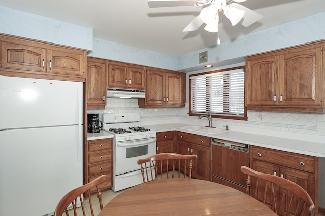 kitchen with light countertops, white appliances, brown cabinetry, and under cabinet range hood