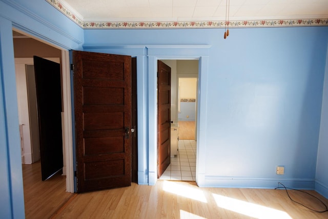 unfurnished bedroom featuring light wood-type flooring, connected bathroom, and baseboards