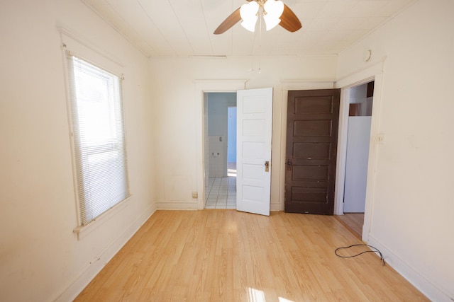 spare room featuring a ceiling fan, light wood-style flooring, and baseboards