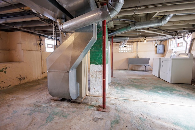 basement with a wealth of natural light, electric panel, a sink, and separate washer and dryer