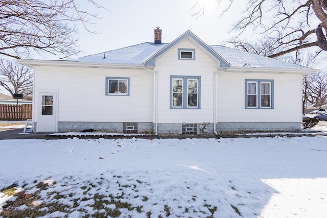 snow covered back of property with a chimney