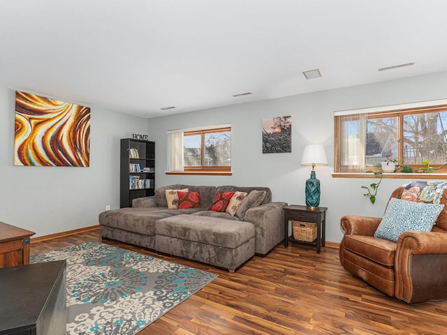 living room featuring visible vents, baseboards, and wood finished floors