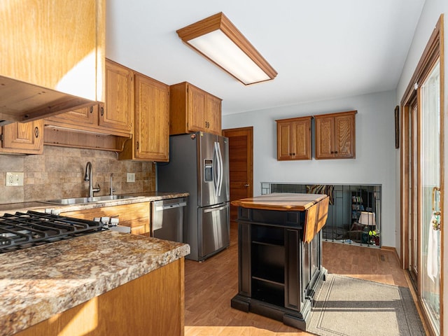 kitchen featuring stainless steel appliances, light wood-style floors, a sink, and brown cabinets