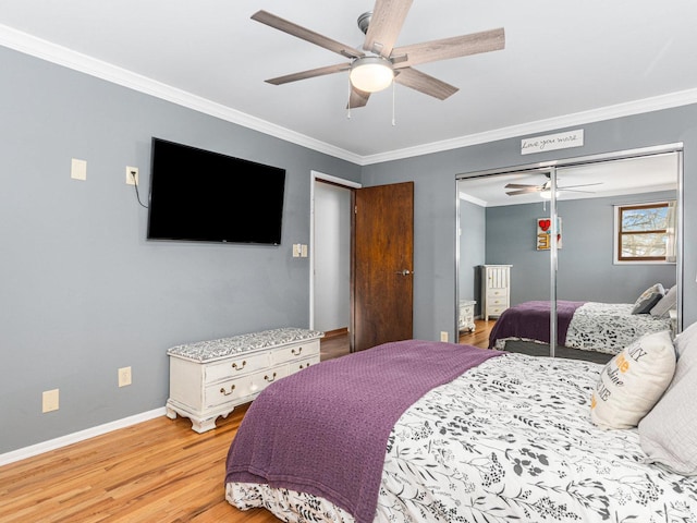 bedroom featuring baseboards, a ceiling fan, ornamental molding, light wood-style floors, and a closet