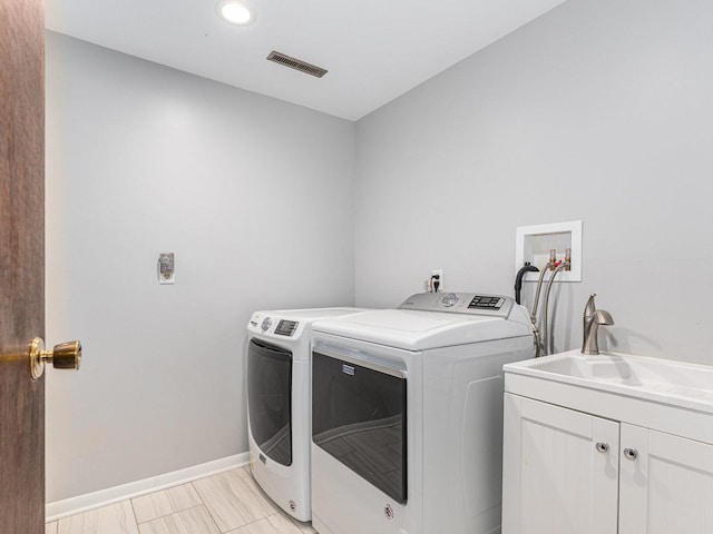 laundry room with a sink, visible vents, baseboards, cabinet space, and washing machine and clothes dryer