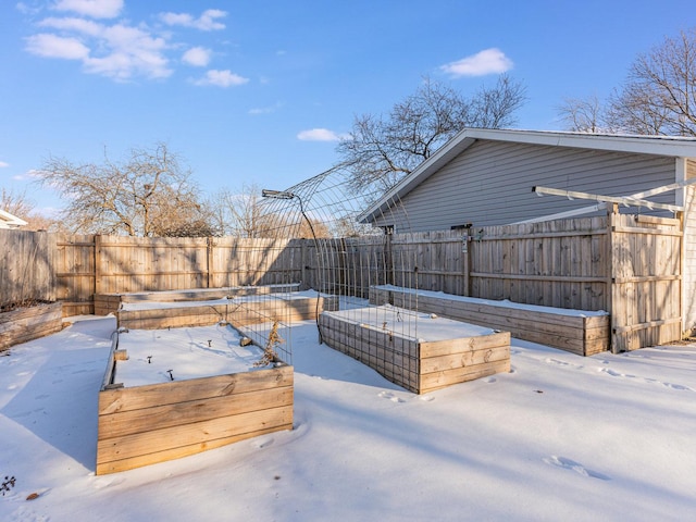 snow covered deck with a fenced backyard and a vegetable garden