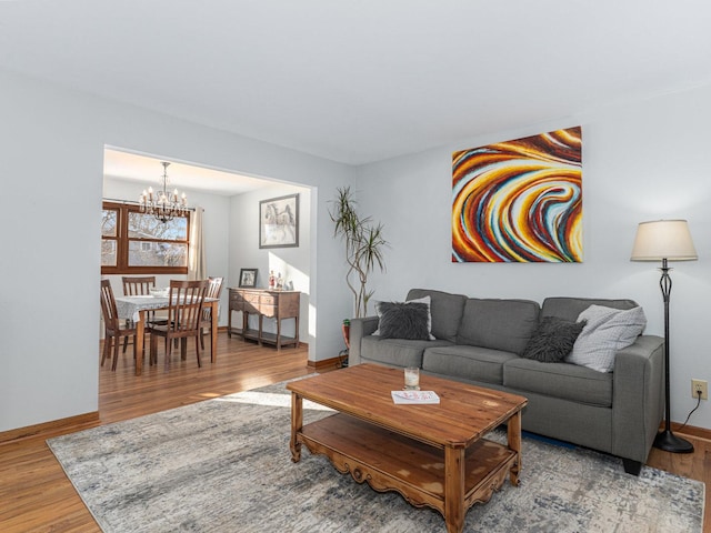 living room featuring a notable chandelier, baseboards, and wood finished floors