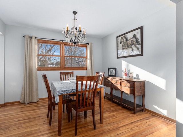 dining room with light wood-style flooring, a chandelier, and baseboards