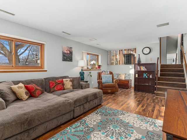 living area featuring stairs, dark wood-type flooring, and visible vents