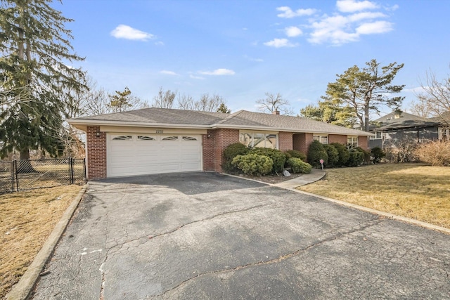 ranch-style home featuring brick siding, a front yard, fence, a garage, and driveway