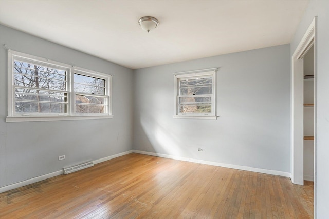 spare room featuring hardwood / wood-style flooring, visible vents, and baseboards