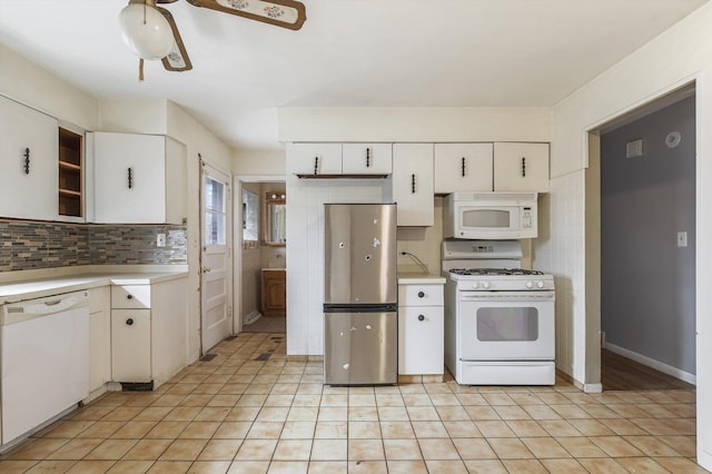 kitchen with white appliances, light tile patterned floors, white cabinets, light countertops, and backsplash