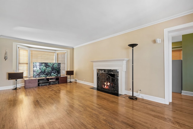 unfurnished living room with a fireplace, baseboards, crown molding, and wood finished floors