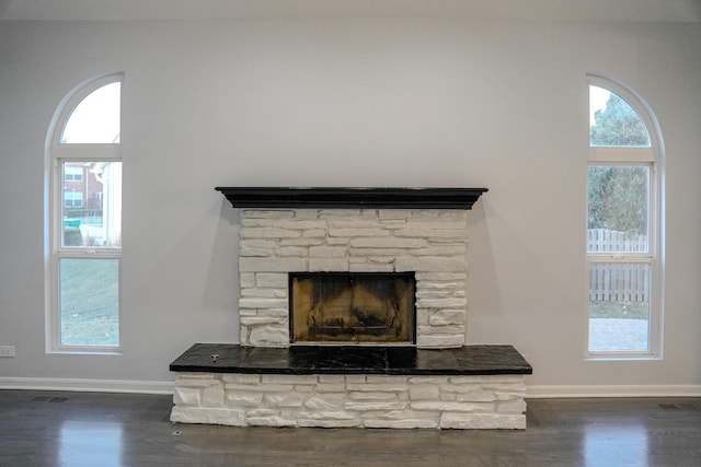 details with visible vents, a fireplace, baseboards, and wood finished floors