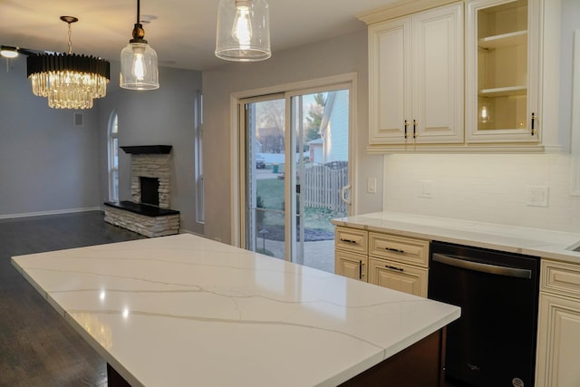 kitchen featuring dishwasher, decorative light fixtures, glass insert cabinets, and light stone countertops