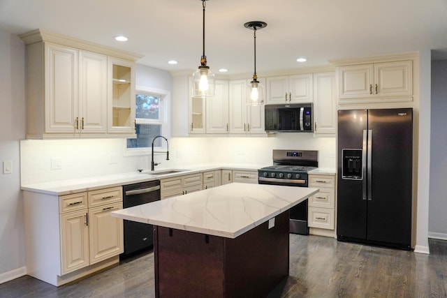 kitchen featuring light stone counters, hanging light fixtures, appliances with stainless steel finishes, glass insert cabinets, and a kitchen island