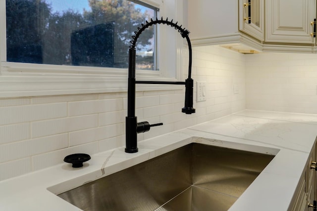 details with a sink, decorative backsplash, and light stone countertops