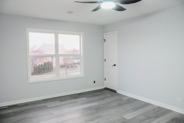 spare room featuring visible vents, baseboards, and wood finished floors