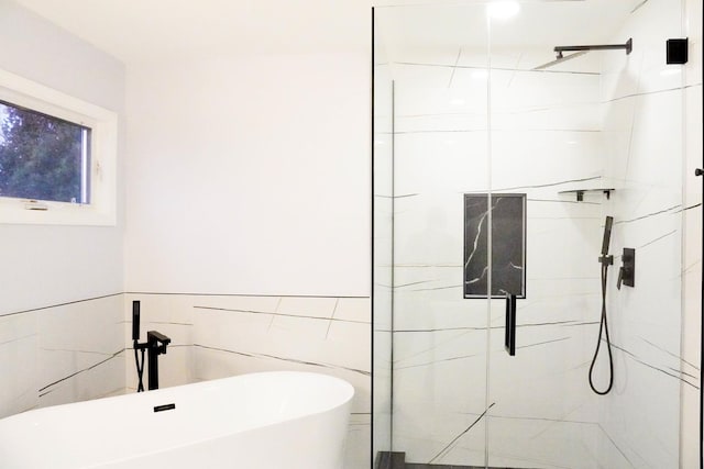 full bathroom with a freestanding bath, a marble finish shower, and tile walls