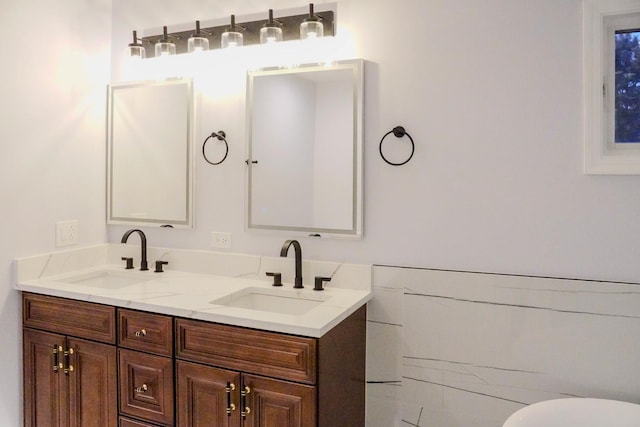 full bath featuring double vanity, a sink, and tile walls