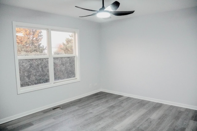 spare room featuring a ceiling fan, visible vents, baseboards, and wood finished floors