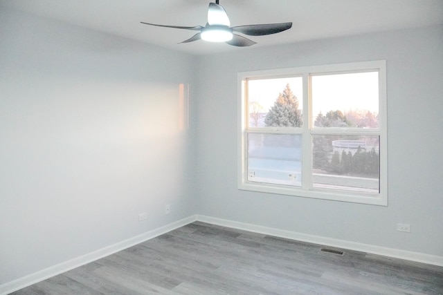 spare room with a ceiling fan, light wood-type flooring, visible vents, and baseboards