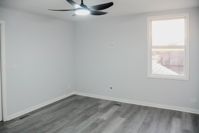 unfurnished room featuring dark wood-style flooring, visible vents, and baseboards