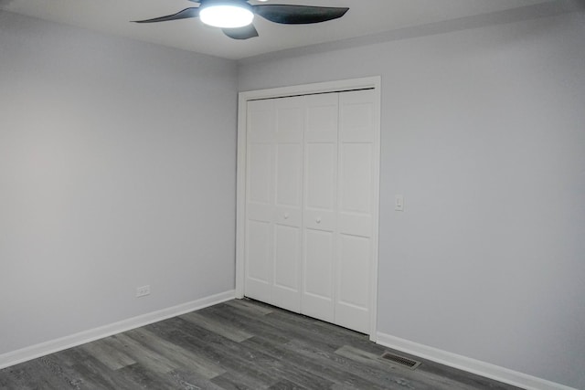 unfurnished bedroom featuring dark wood-style floors, a ceiling fan, baseboards, and a closet